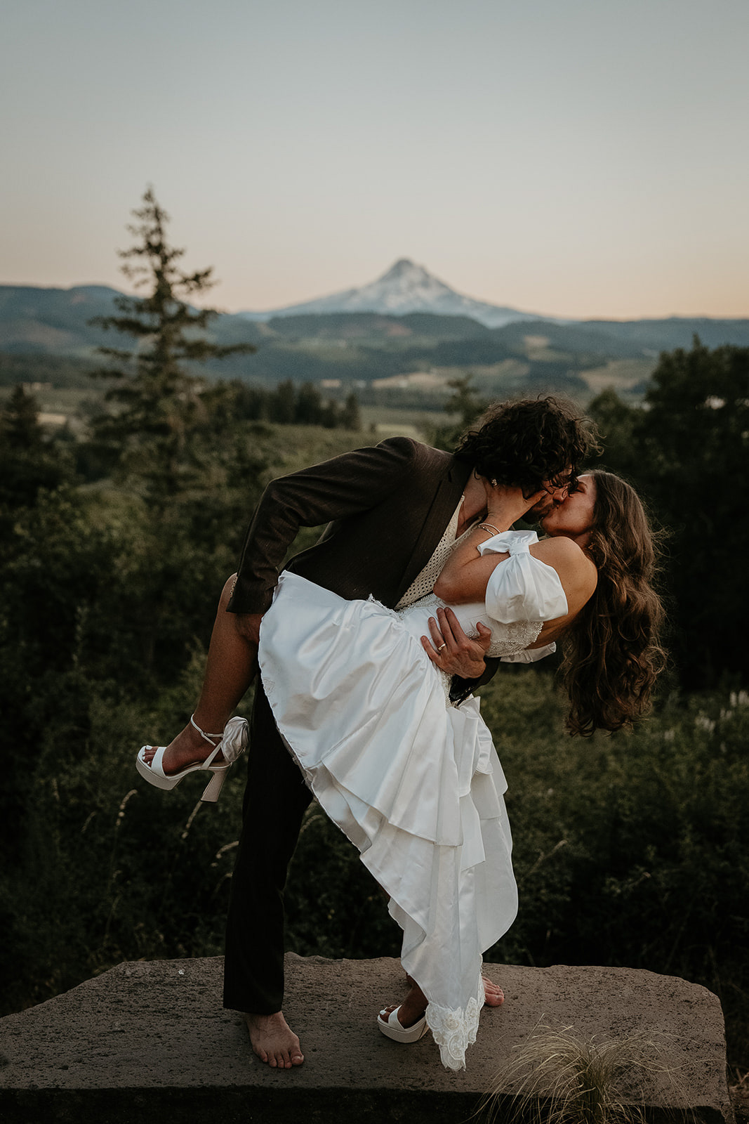 newlyweds kissing with views of mount hood behind them during their vintage inspired wedding.