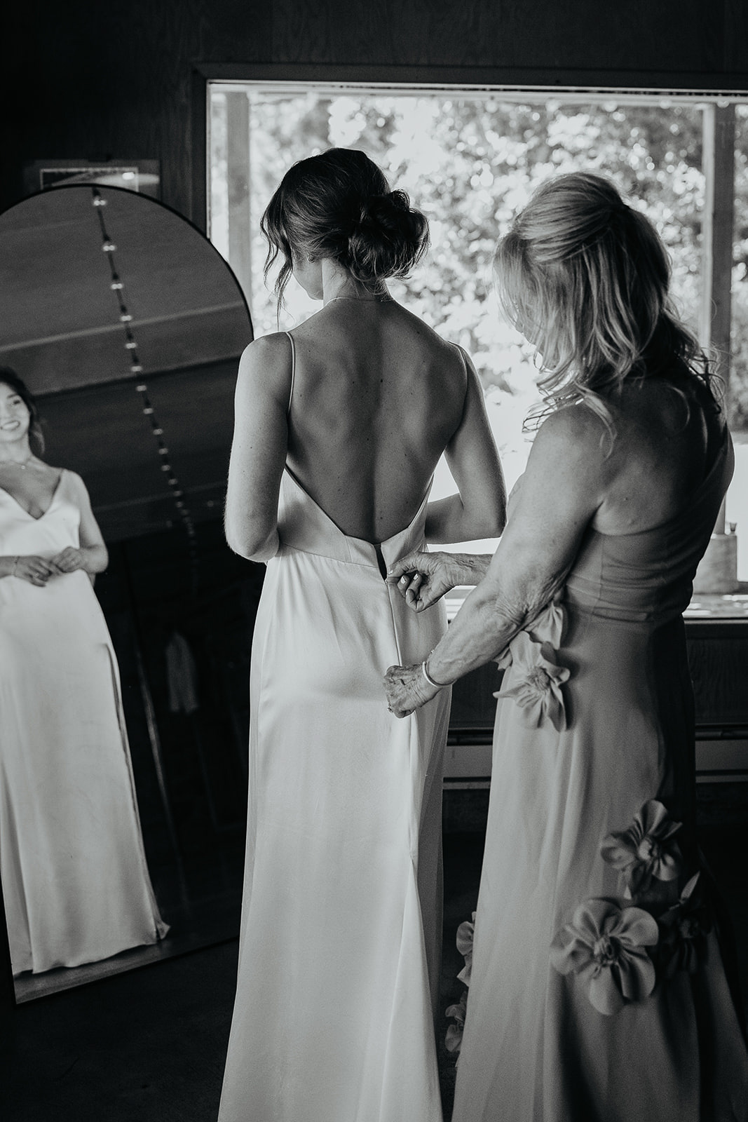 a bridesmaid helping zip up the bride's dress