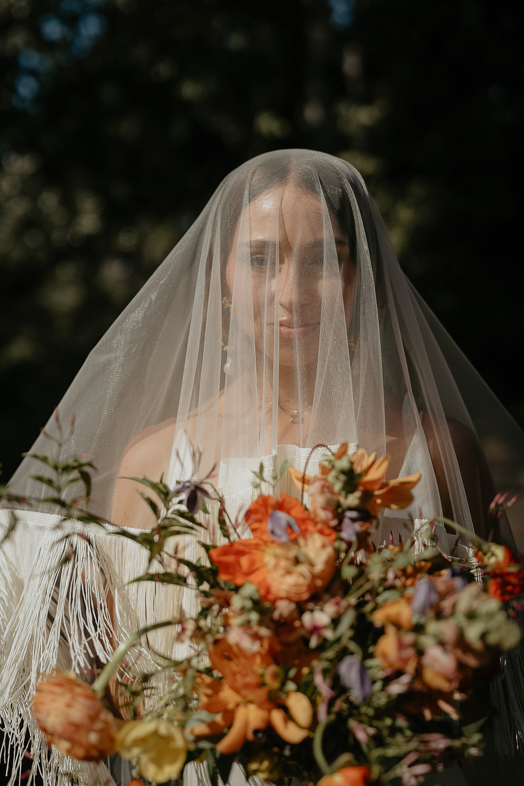 the bride holding a bouquet of flowers with her veil over her head.