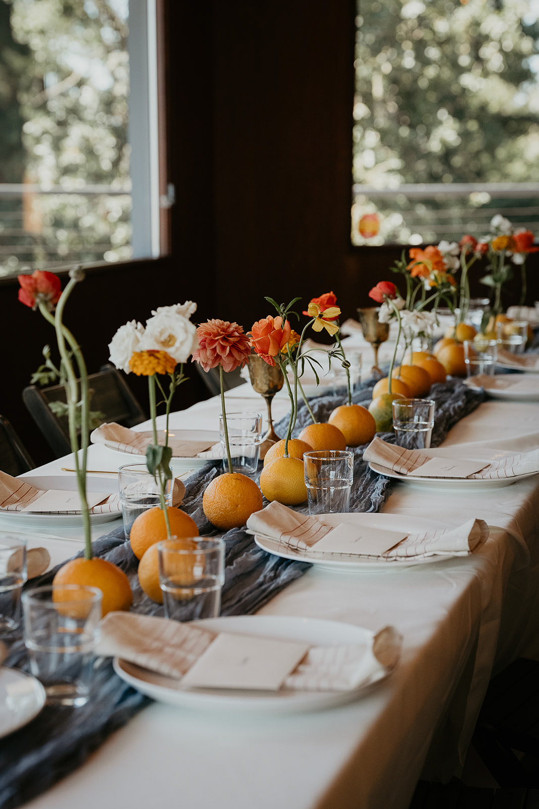 a wedding dinner table decorated with oranges and flowers.