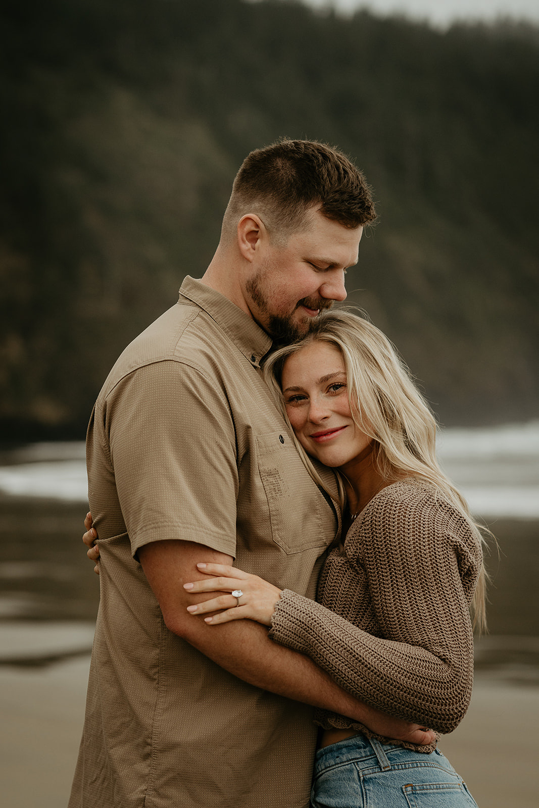 couple hugging on the beach in Oregon after a classic surprise proposal, one of the ways to propose.