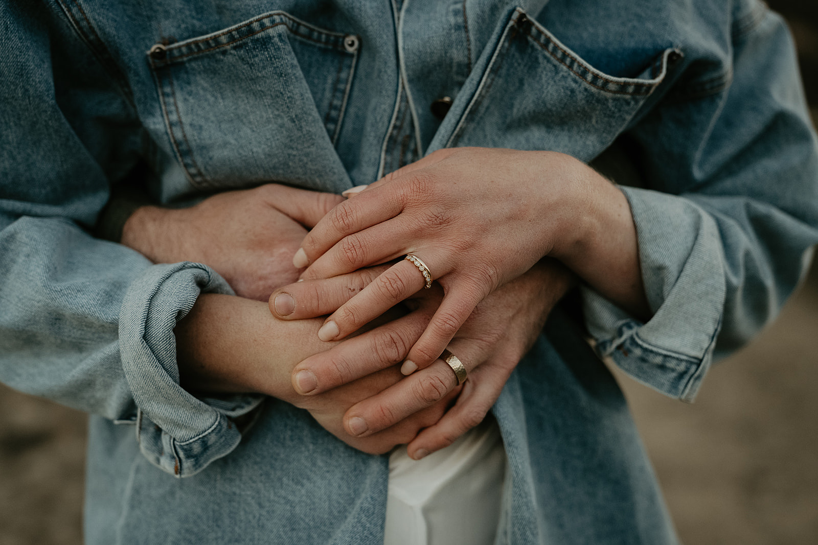 husband hugging wife from behind with their hands interlaced.