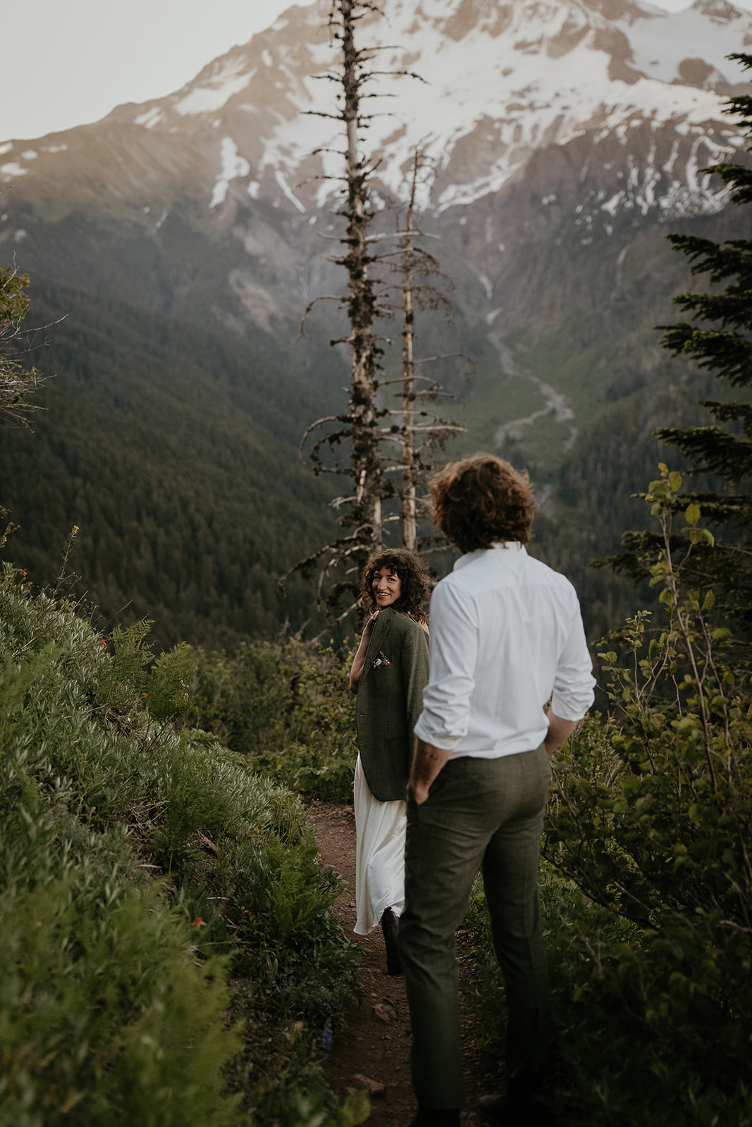 couple walking along a hiking trail in the mountains during their wedding anniversary photoshoot.