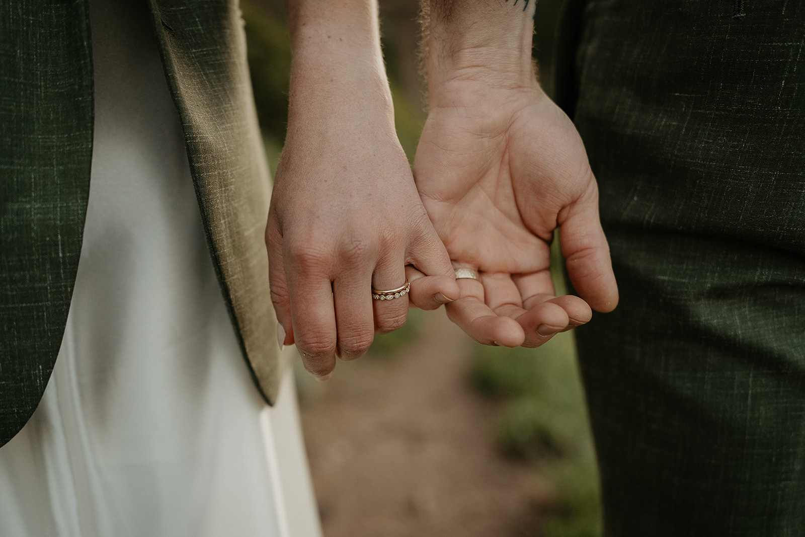 couple holding pinkies showing off their wedding rings.