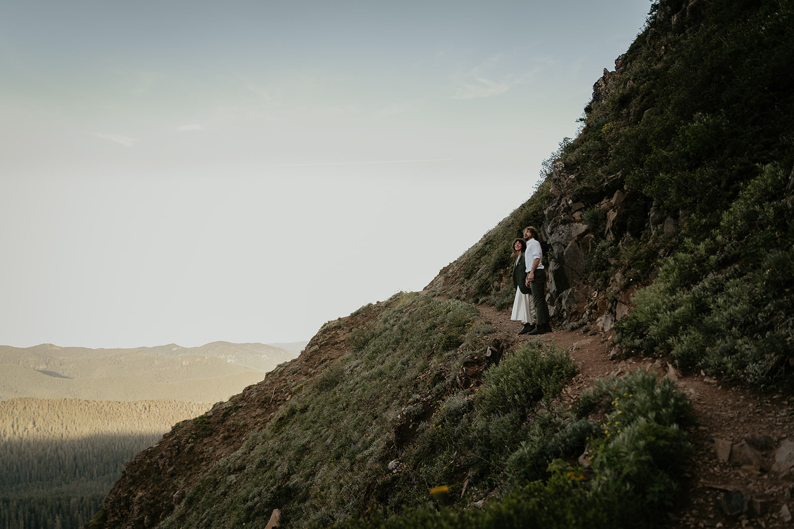 couple standing on a mountain trail enjoying the view.