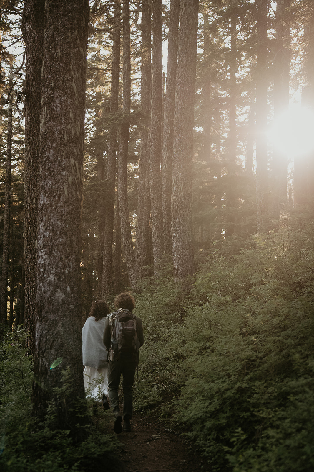 couple walking through a forest during their wedding anniversary photoshoot.