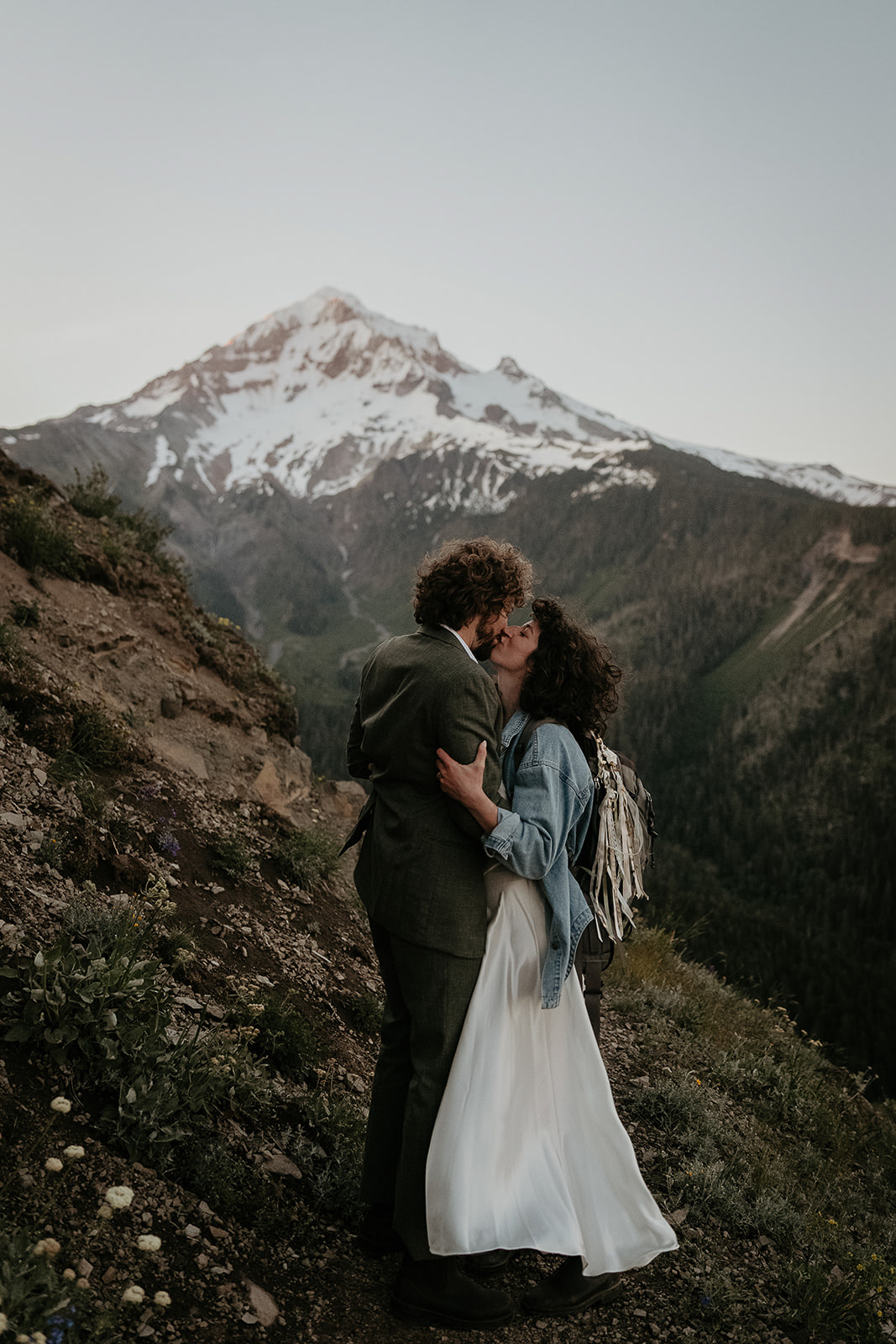 couple kissing on hiking trail with mount Hood in the background during their wedding anniversary photoshoot.
