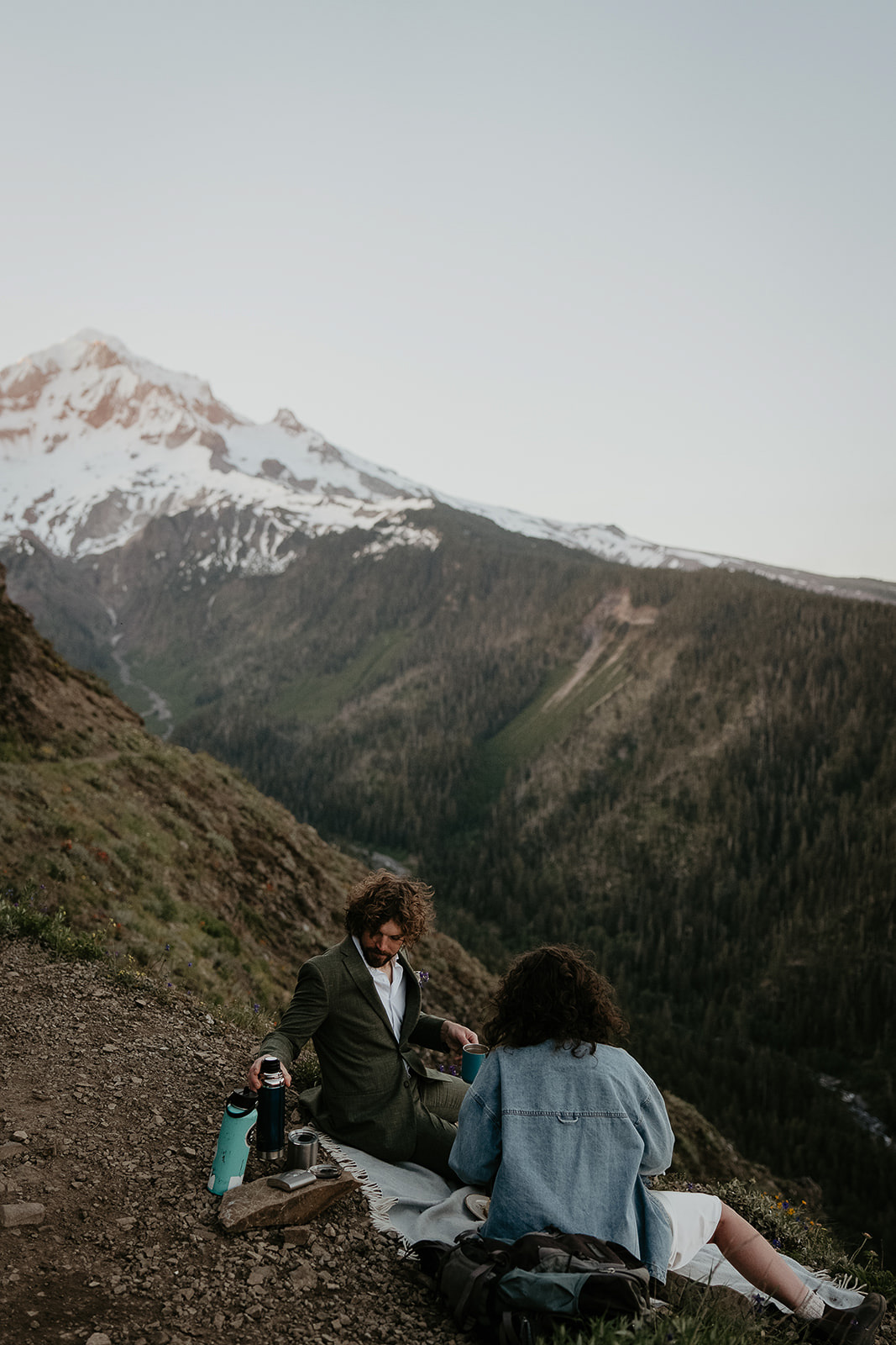 Couple sitting on a picnic blanket with mount Hood in the background during their wedding anniversary photoshoot.