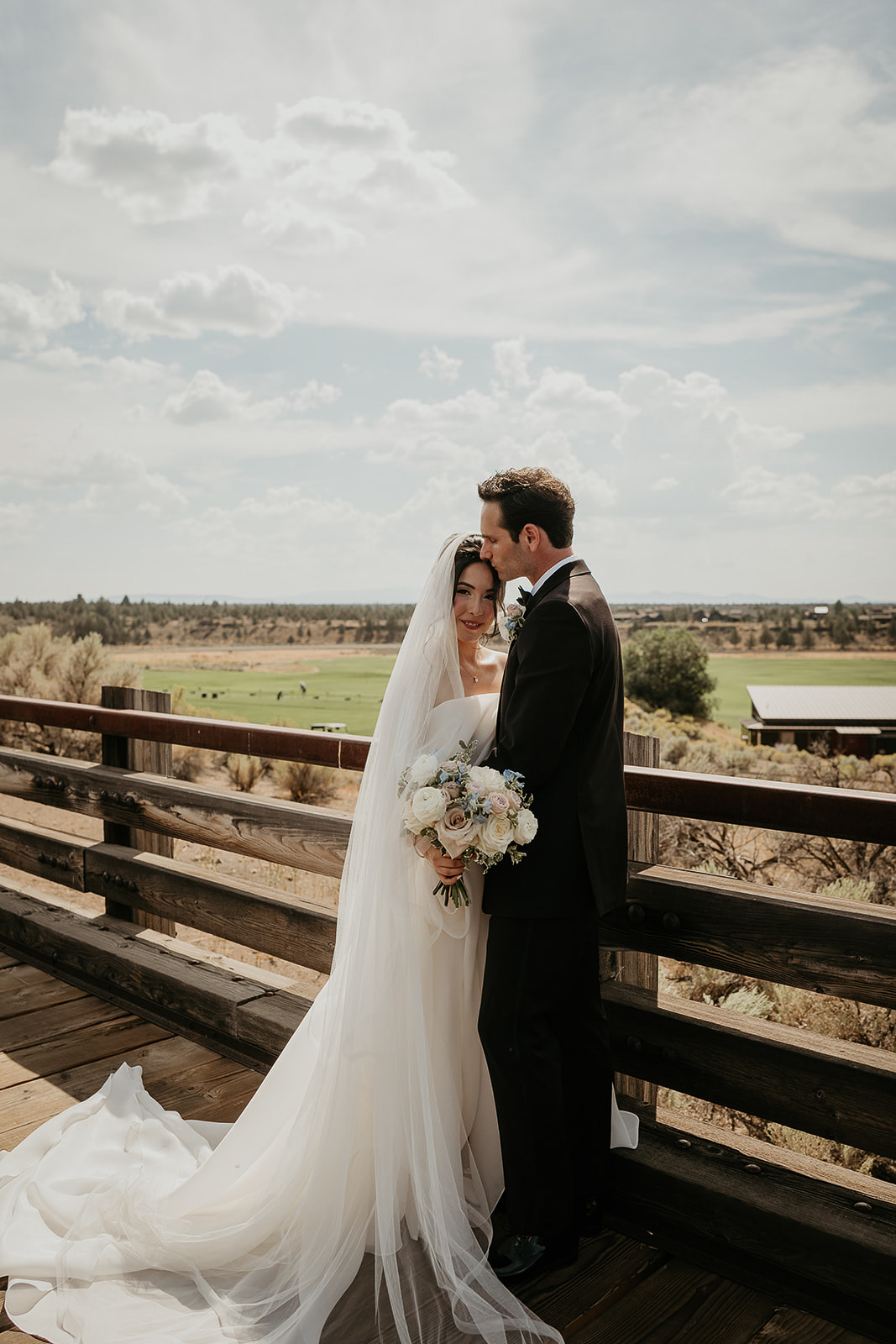 Newlyweds hugging on a tressle bridge at Brasada Ranch, one of the best wedding venues in Oregon.