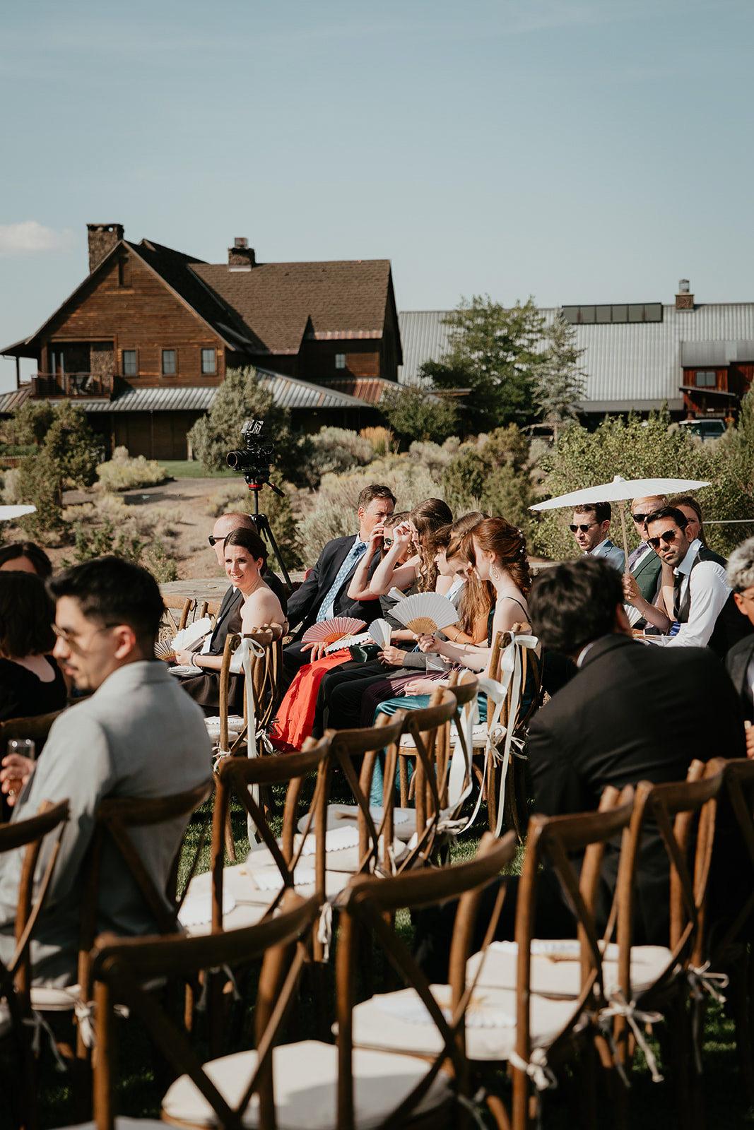 wedding guests sitting waiting for the ceremony to begin with Brasada Ranch building in the background.