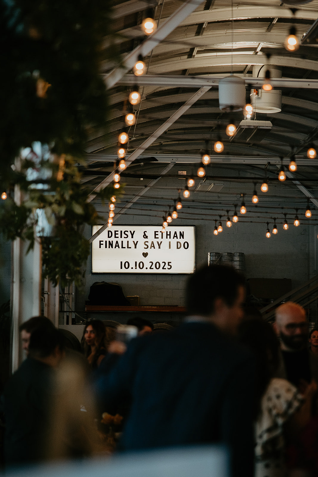 a neon sign that reads "Deisy and Ethan Finally Say I Do 10.10.2025" inside Coopers Hall.