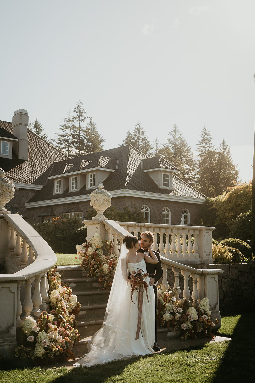 Newlyweds kissing on the staircase outside Chateau de Michellia, one of the best wedding venues in Oregon.
