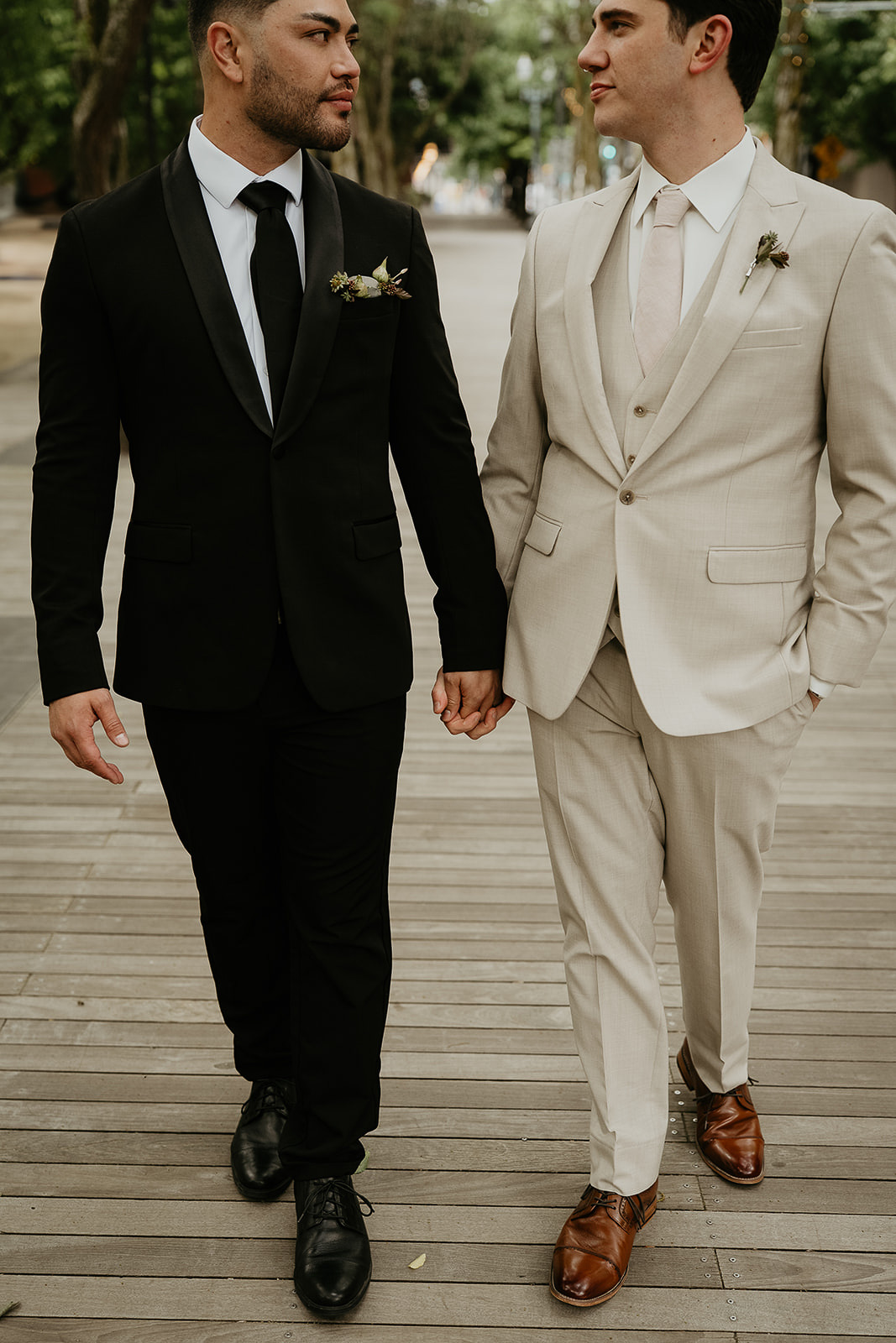 newlyweds holding hands walking on a wooden floor.