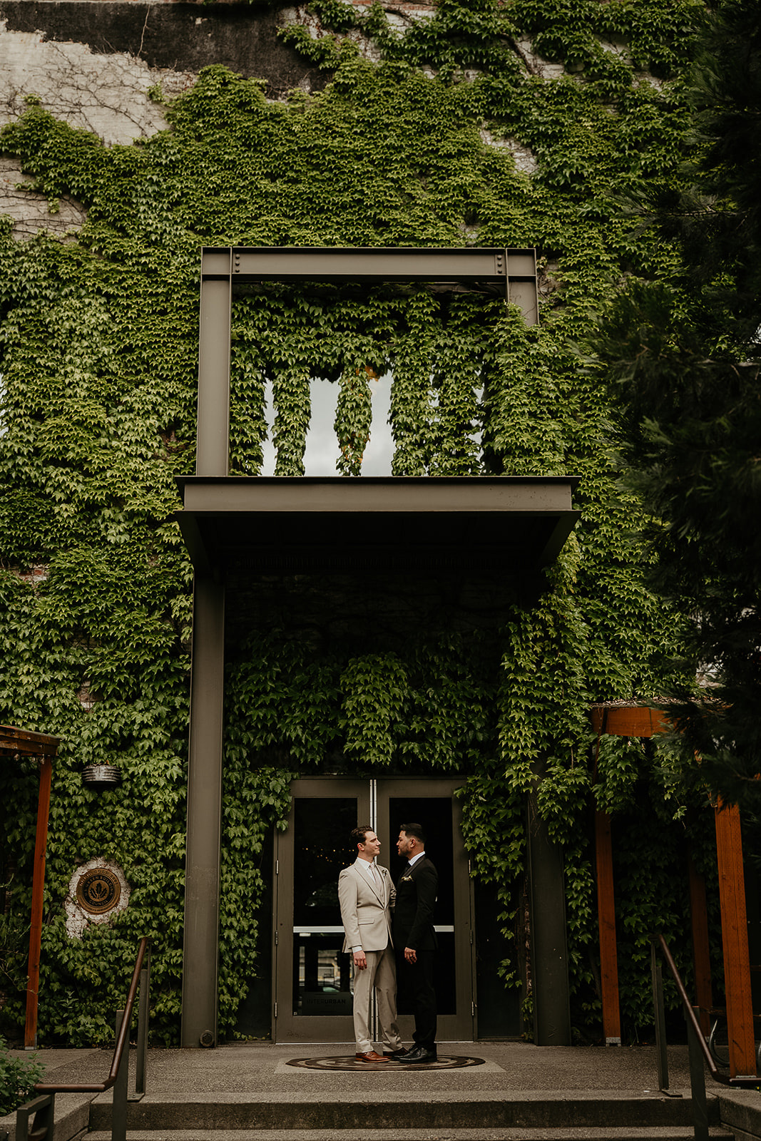 newlyweds standing under an ivy-covered wall for an Ecotrust wedding styled shoot.