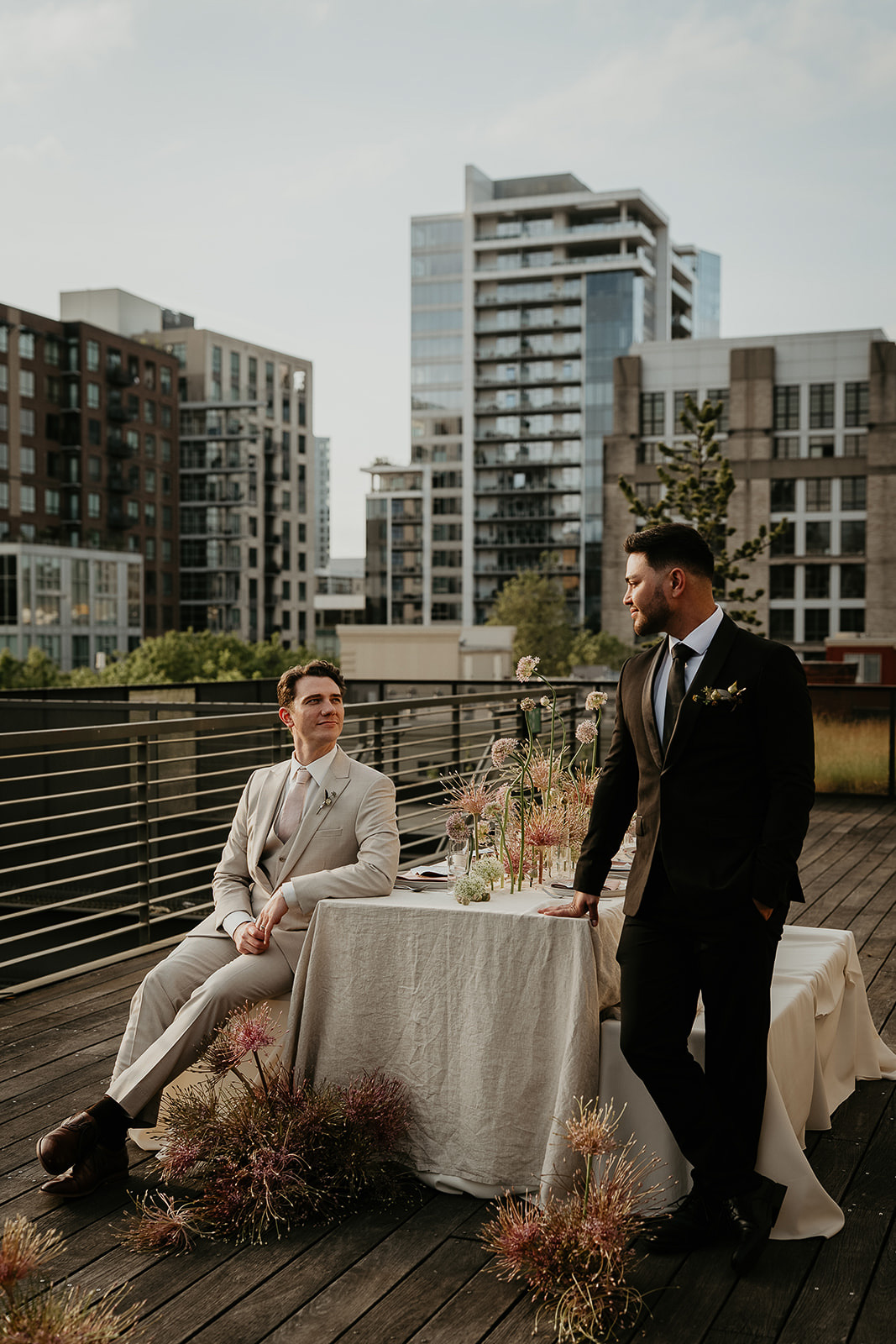 Newlyweds sitting at a decorated table on a rooftop for an Ecotrust wedding styled shoot.