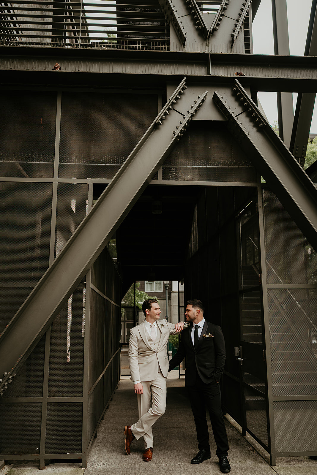 Newlyweds standing under metal I beams at the Ecotrust wedding venue.