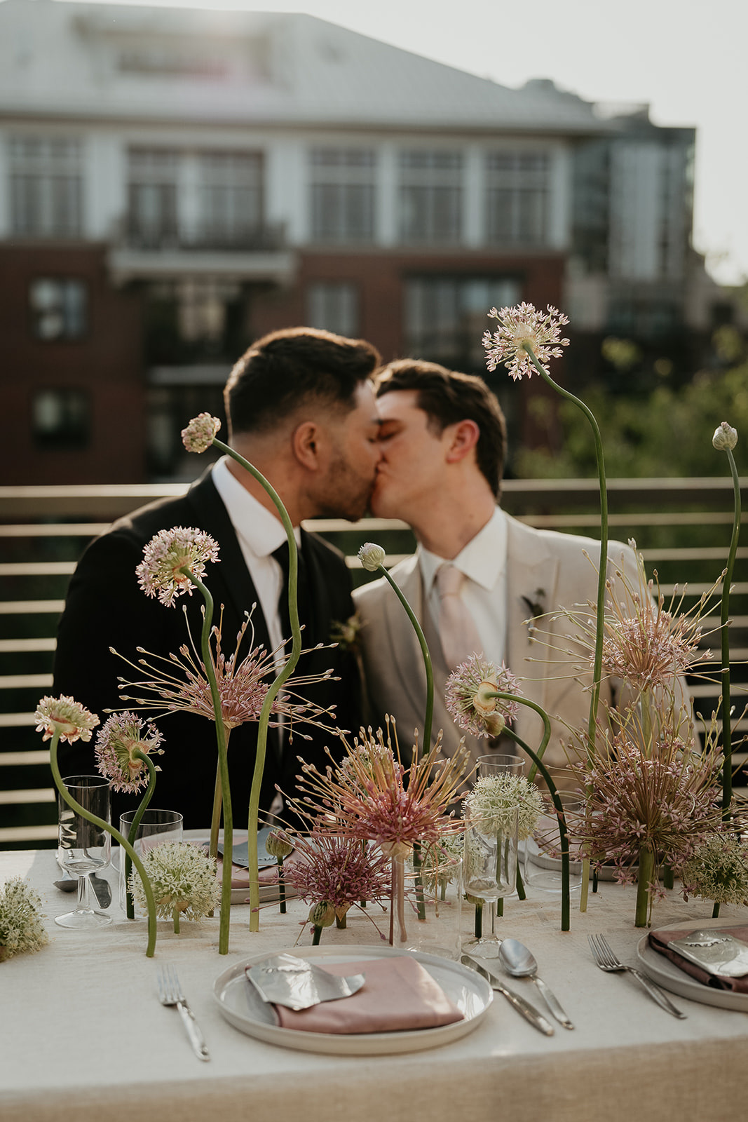 newlyweds kissing in front of an elaborate tablescape for an Ecotrust wedding styled shoot.