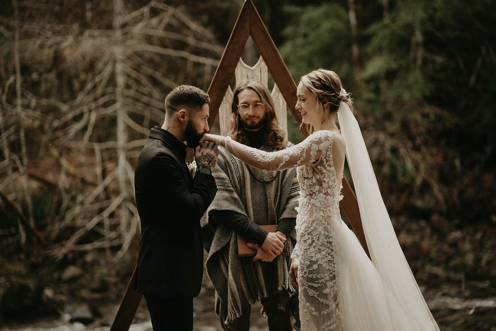 Groom kissing bride's hand during elopement ceremony at Mt Rainier