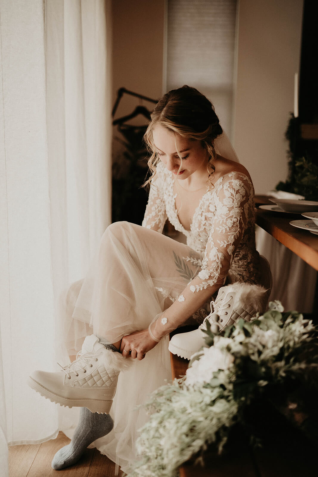 Bride putting on white snow boots for mount rainier elopement
