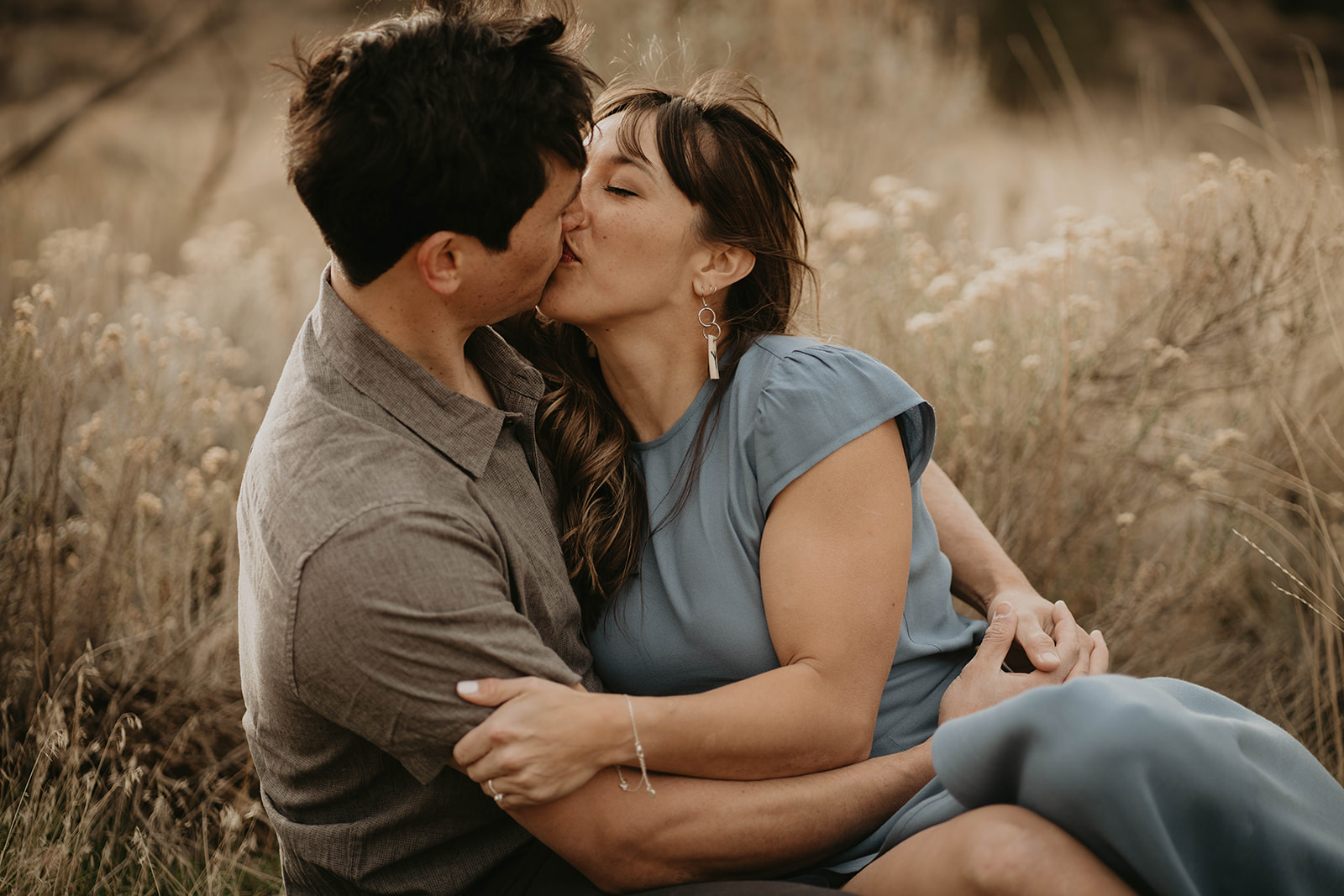 Couple kissing in the field during rock climbing engagement session