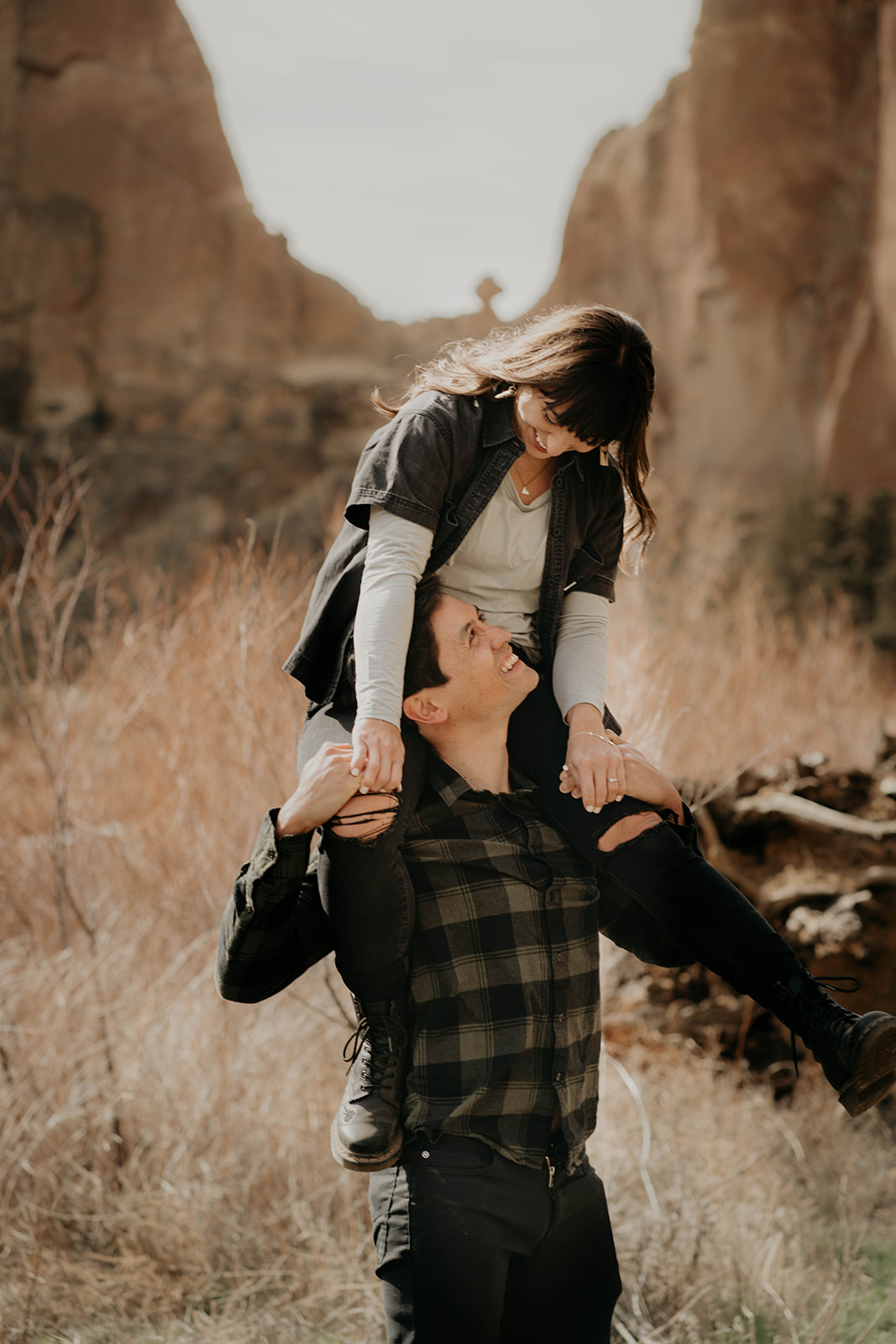 Woman sitting on man's shoulders during engagement session at Smith Rock