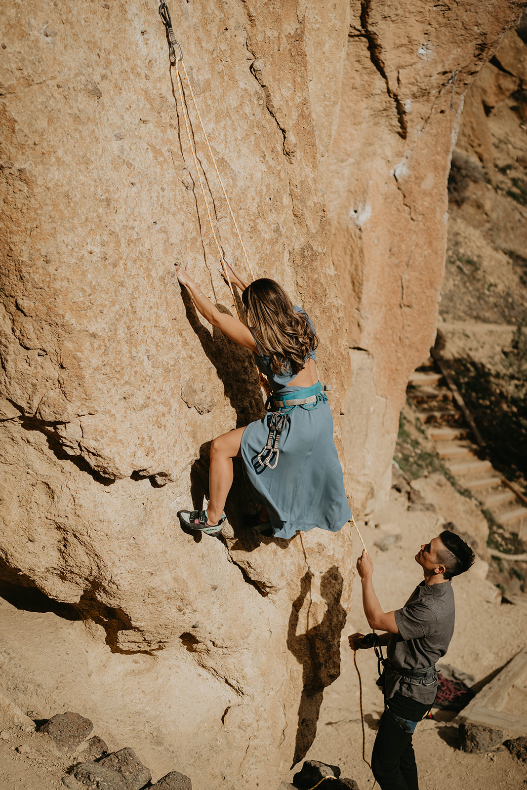 Woman in blue dress rock climbing at Smith Rock State Park
