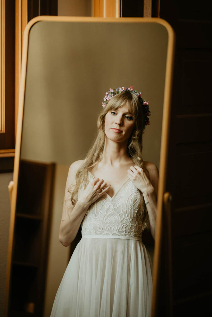 Bride wearing floral crown looking at herself in the mirror 