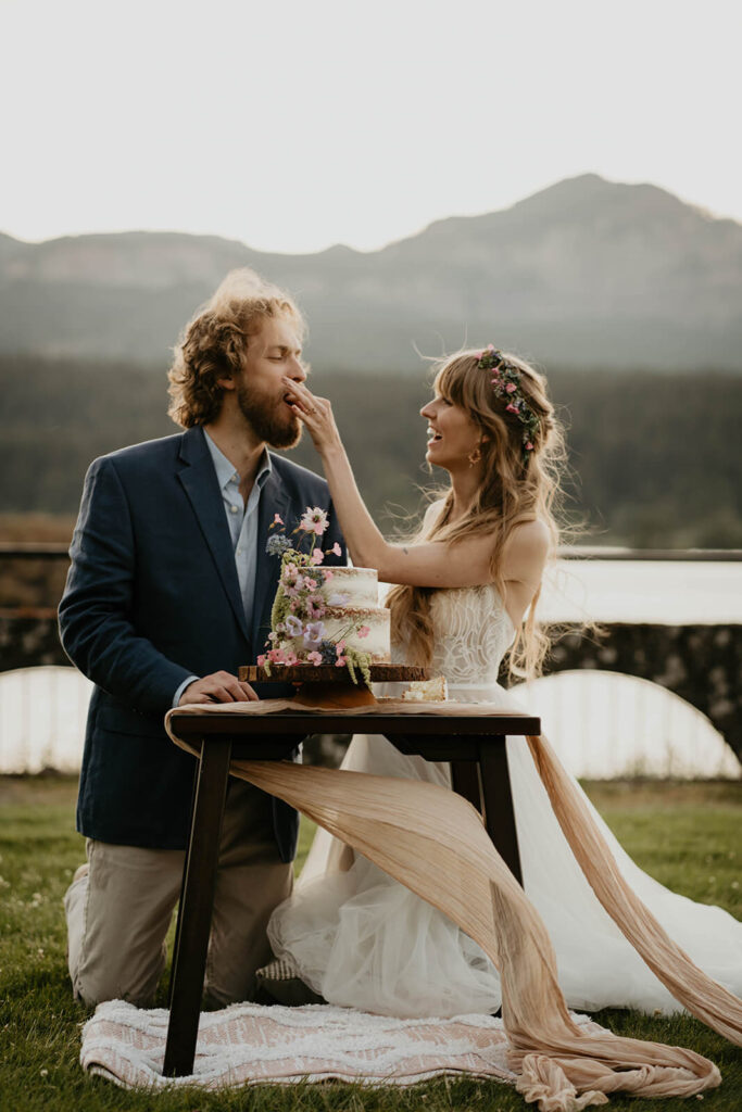 Bride and groom eat cake during outdoor styled wedding shoot