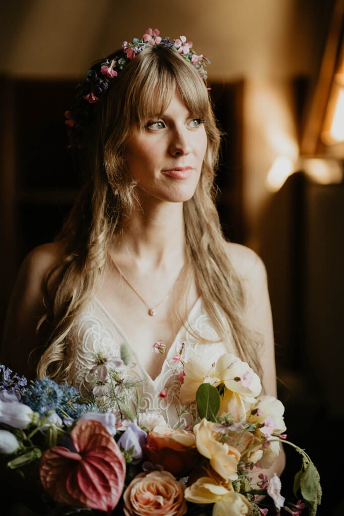 Bride wearing floral crown and holding colorful floral bouquet