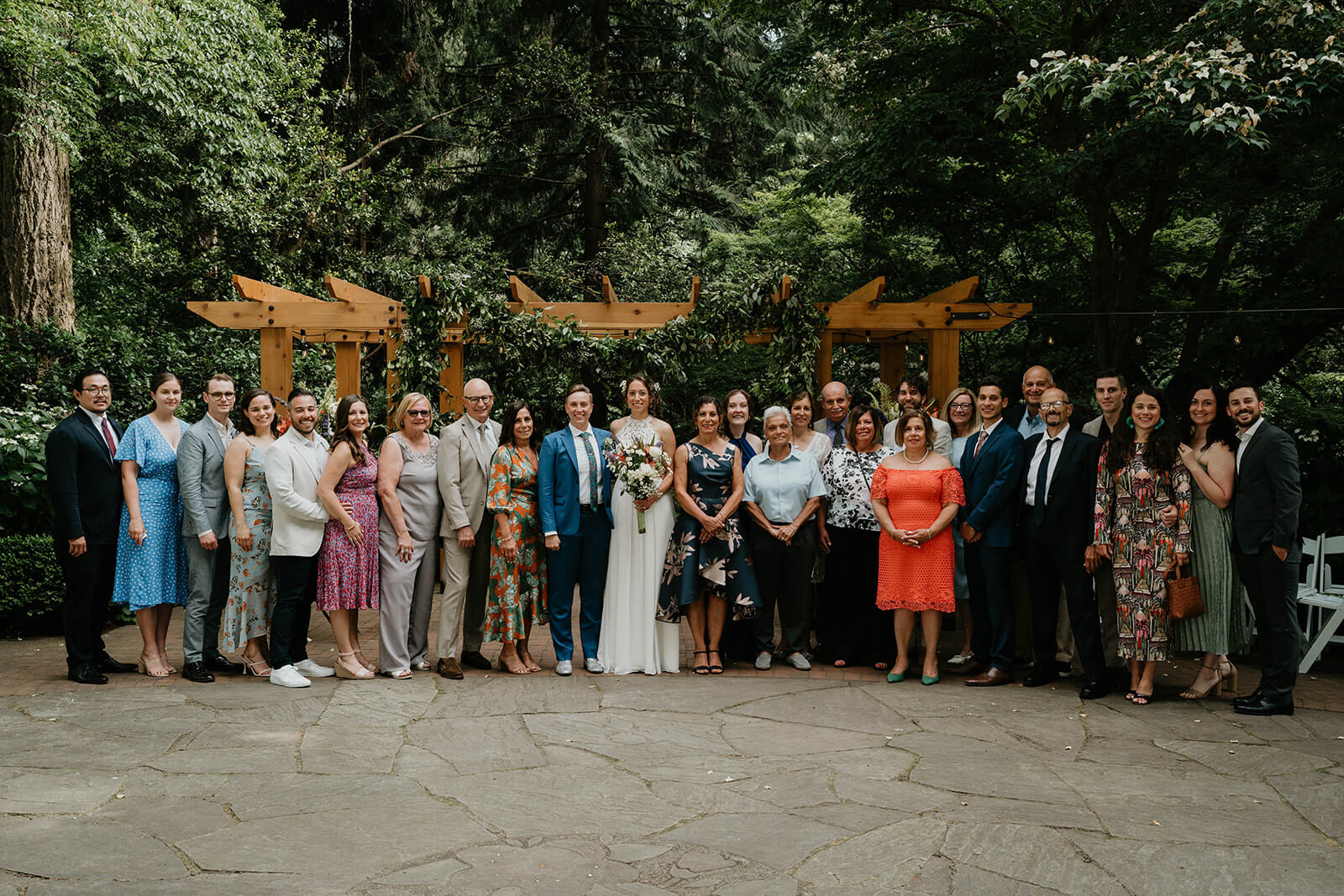 Two brides pose for wedding portraits with family and friends