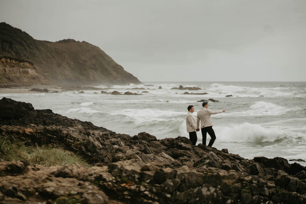 Two groom holding hands and looking out into the ocean on the Oregon Coast
