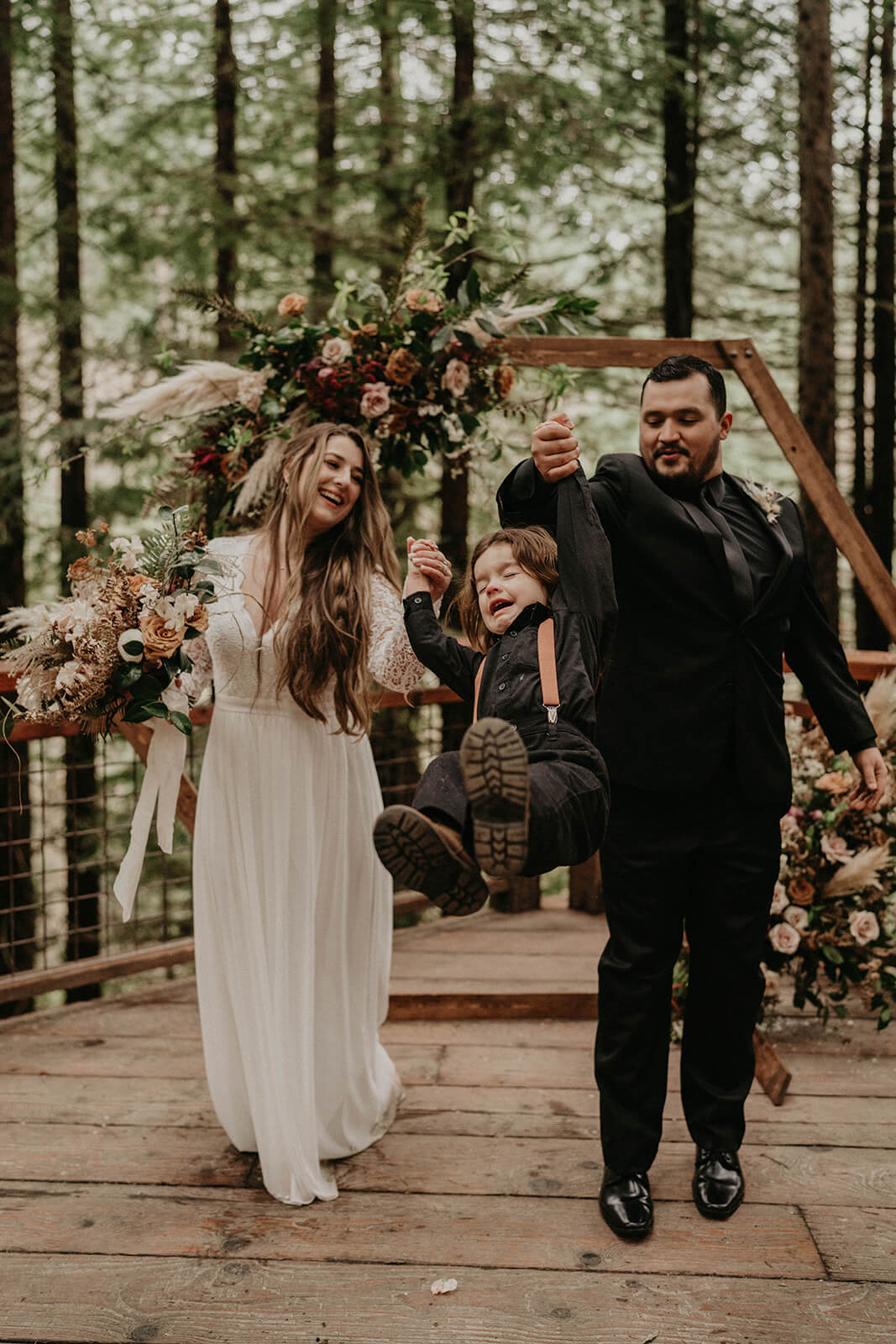 Bride and groom swing their son at Hoyt Arboretum wedding