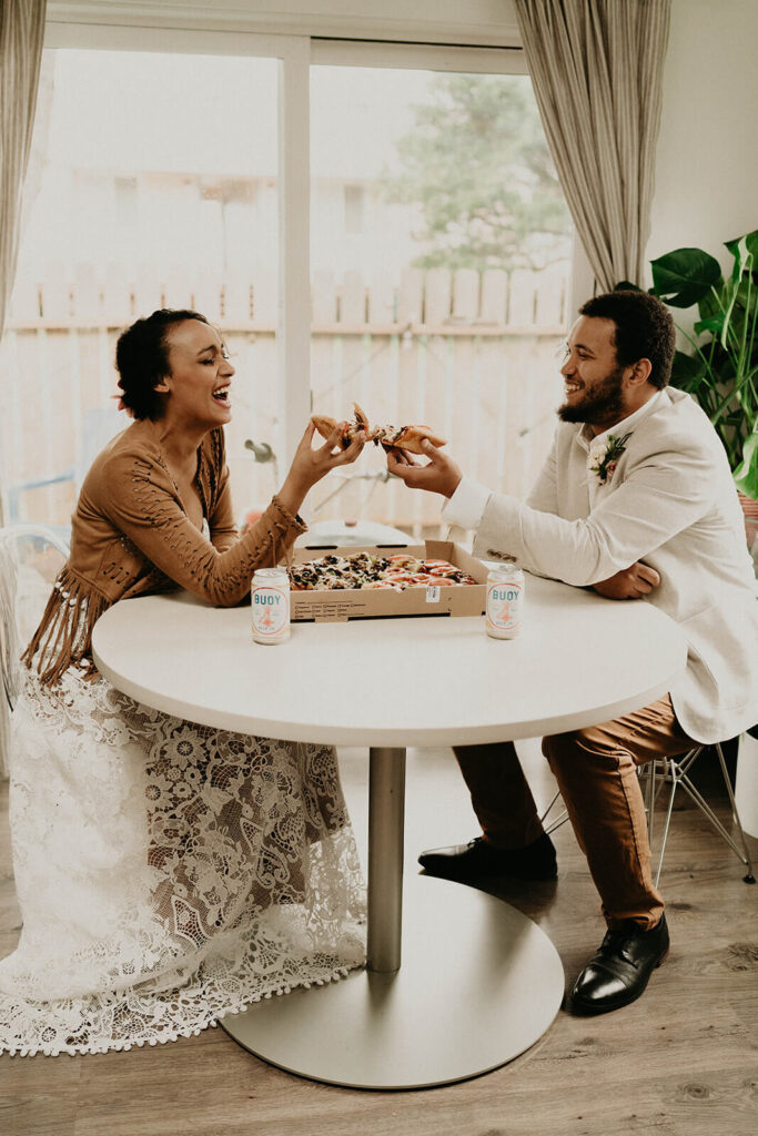 Bride and groom laughing and eating pizza at their Oregon coast elopement