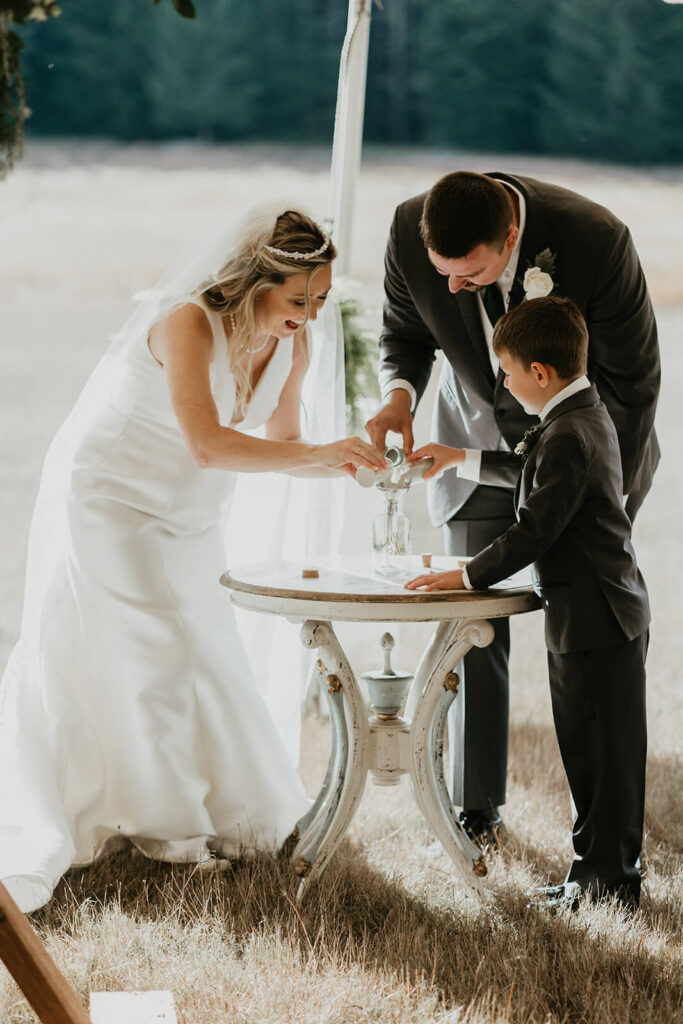 Bride and groom pour sand into a jar with their son during Oregon wedding ceremony