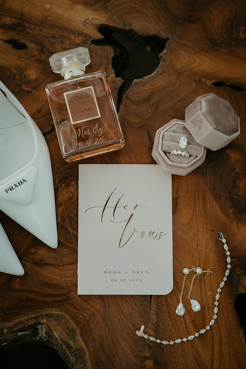 a flat lay with wedding rings, vows, perfume, and heels. 