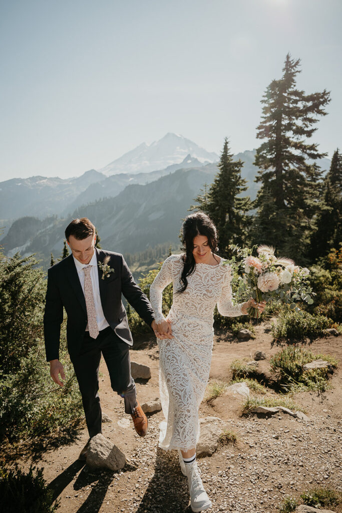 the bride and groom walking in the mountains. 