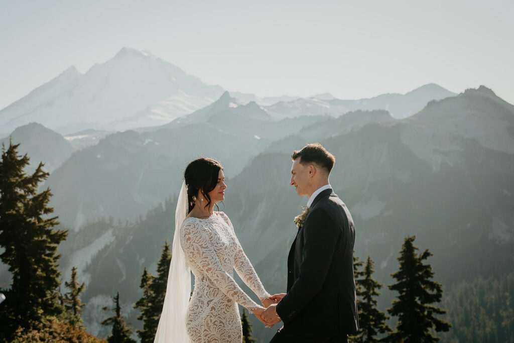 the bride and groom holding hand and staring lovingly into each other's eyes during their North Cascades elopement. 