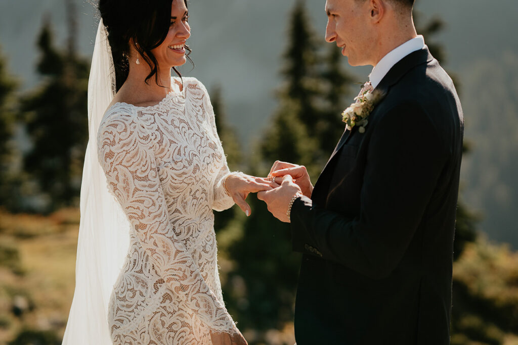 The groom putting on the bride's wedding ring. 