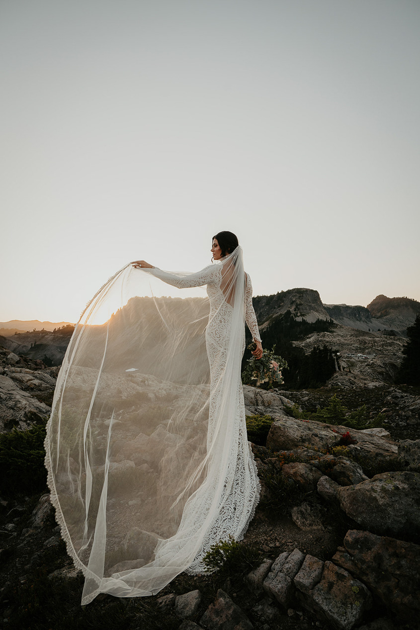 the bride showing off veil in the mountains. 