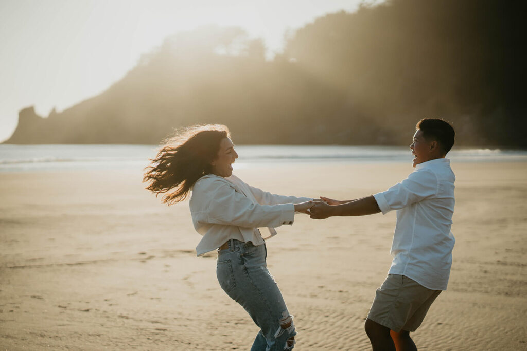 Two women dancing on the beach during Oregon Coast engagement session