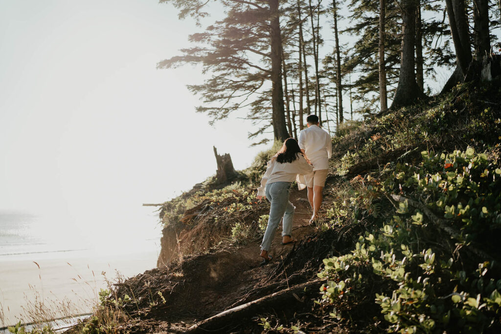 Two women holding hands, walking up a hill during Oregon engagement photos