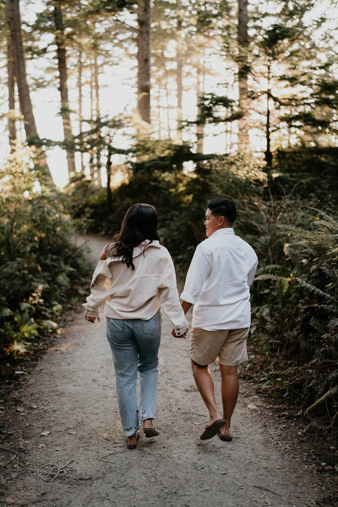 Two women holding hands walking down a path for Oregon engagement session