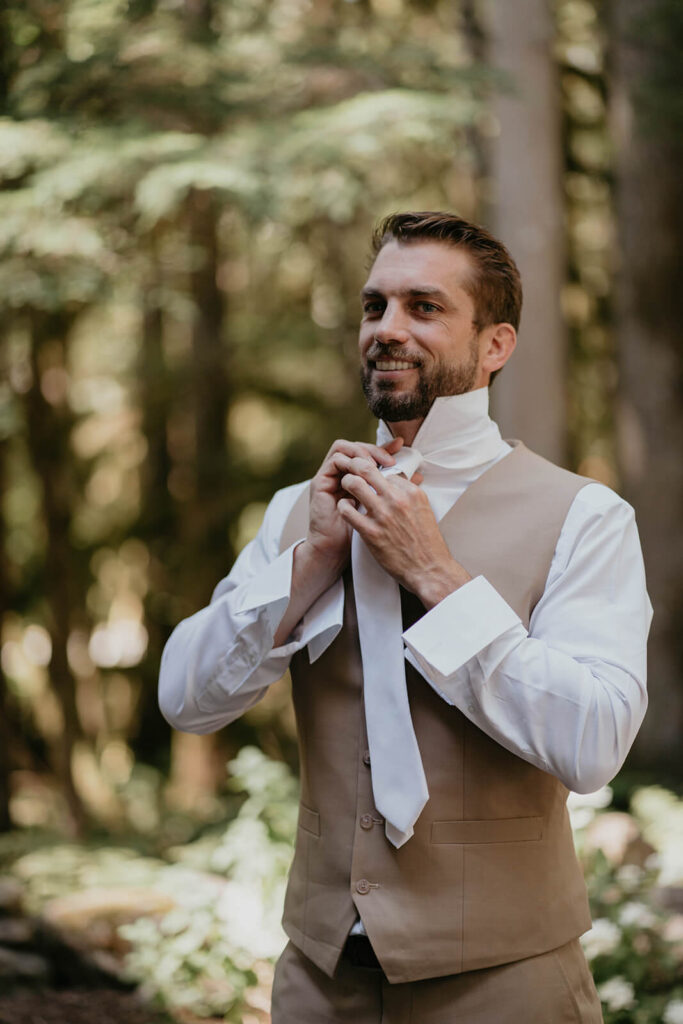 Groom tying white tie for North Cascades elopement