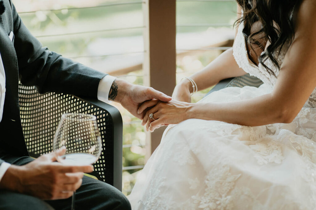 Bride and groom hold hands while drinking wine at Furioso Vineyards