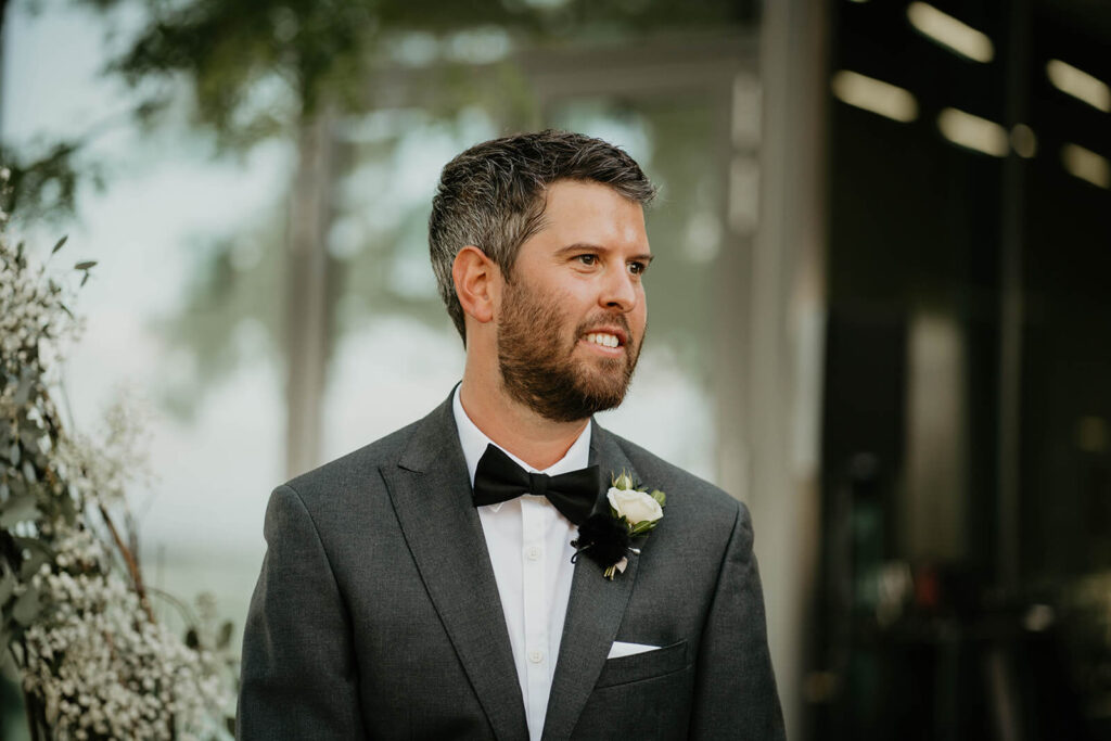 Groom watching bride walk down the aisle at outdoor wedding ceremony