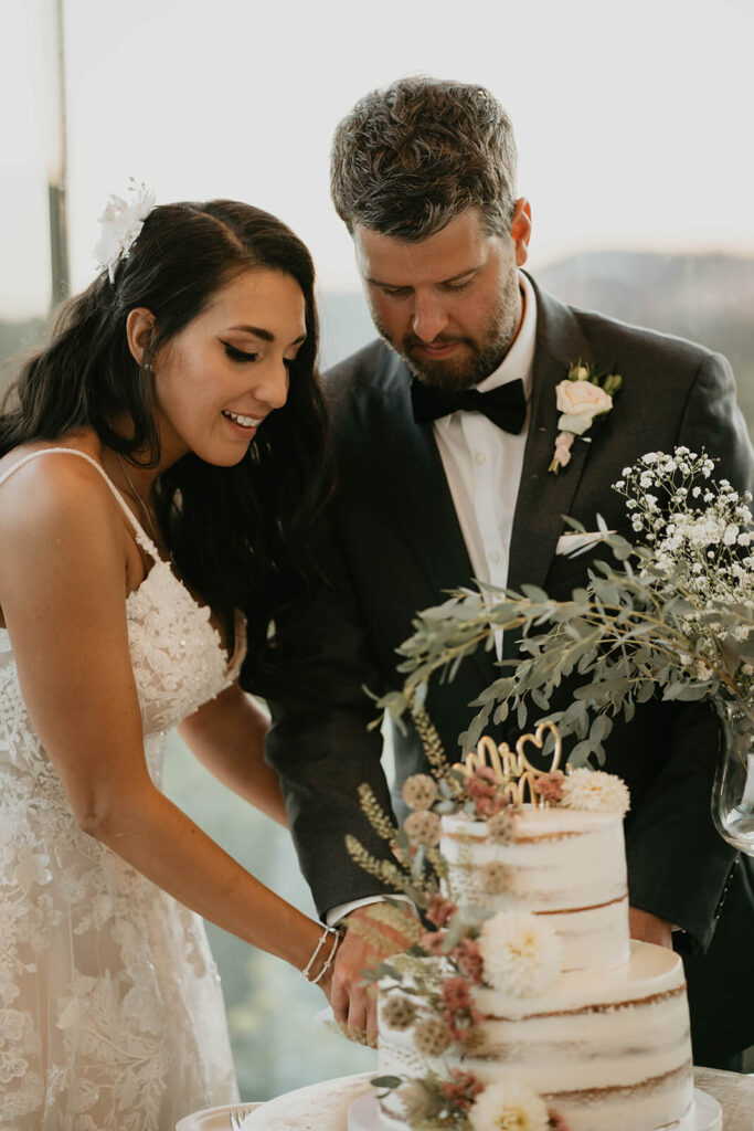 Bride and groom cutting white wedding cake at Oregon vineyard wedding