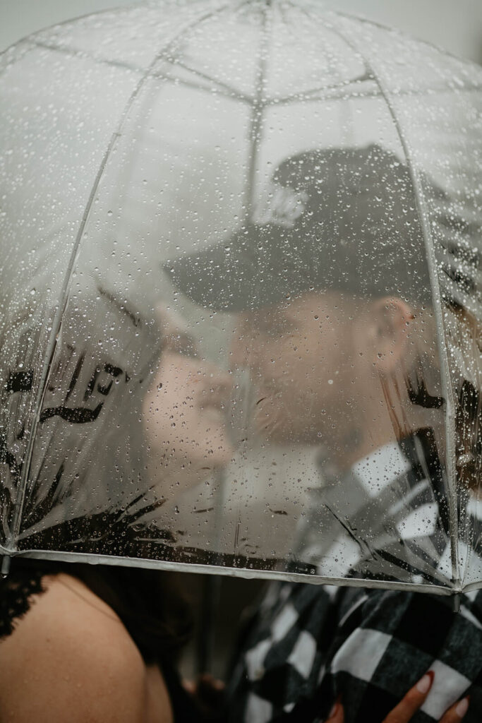 Couple kissing under clear umbrella at Mt Hood