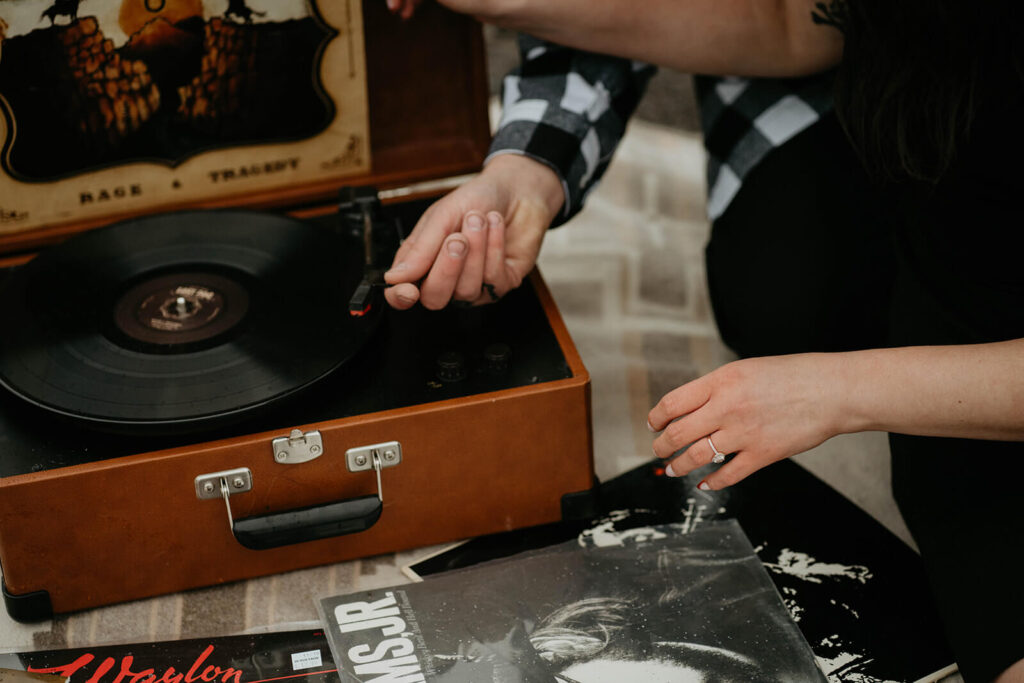 Couple adjusting records on portable record player