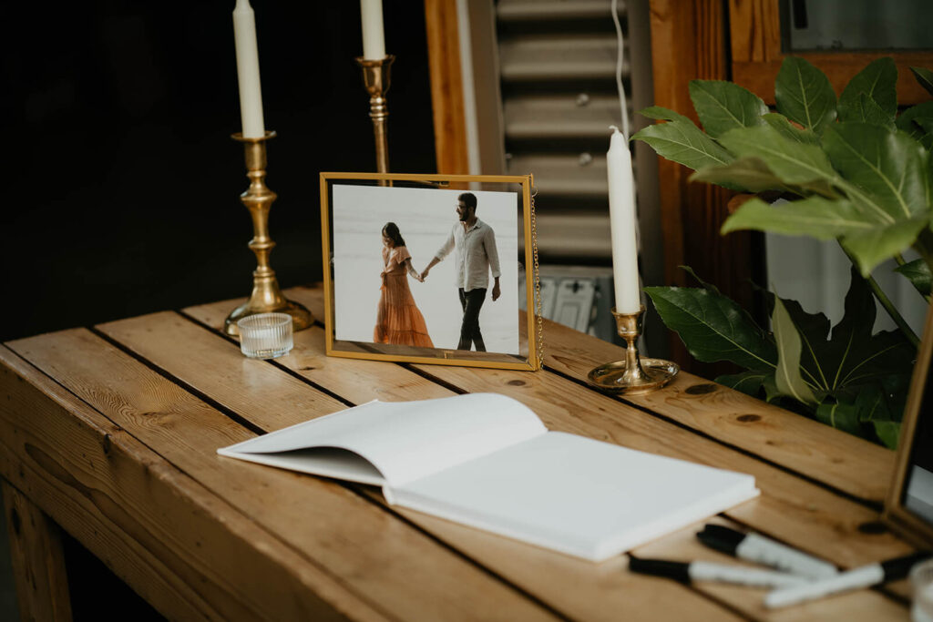 Guest book sitting on wood table with gold candlesticks 