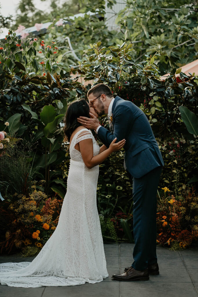 Bride and groom kiss during botanical wedding ceremony 